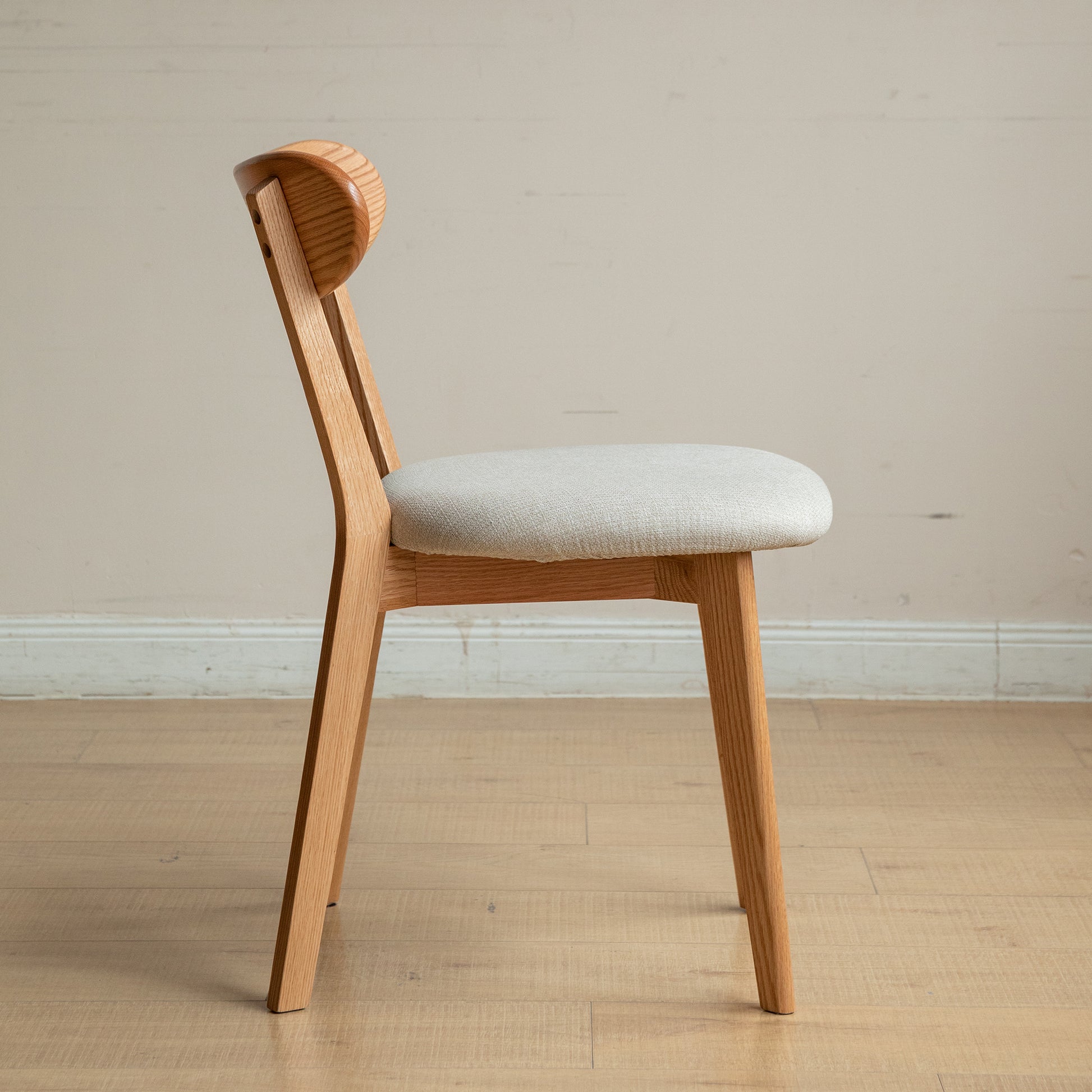 Light oak dining chair with a curved backrest and upholstered seat