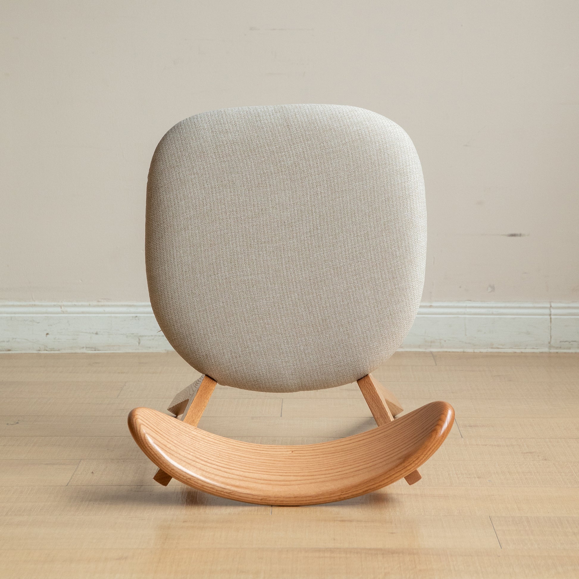 Textured light grey upholstered rocking chair with curved wooden base