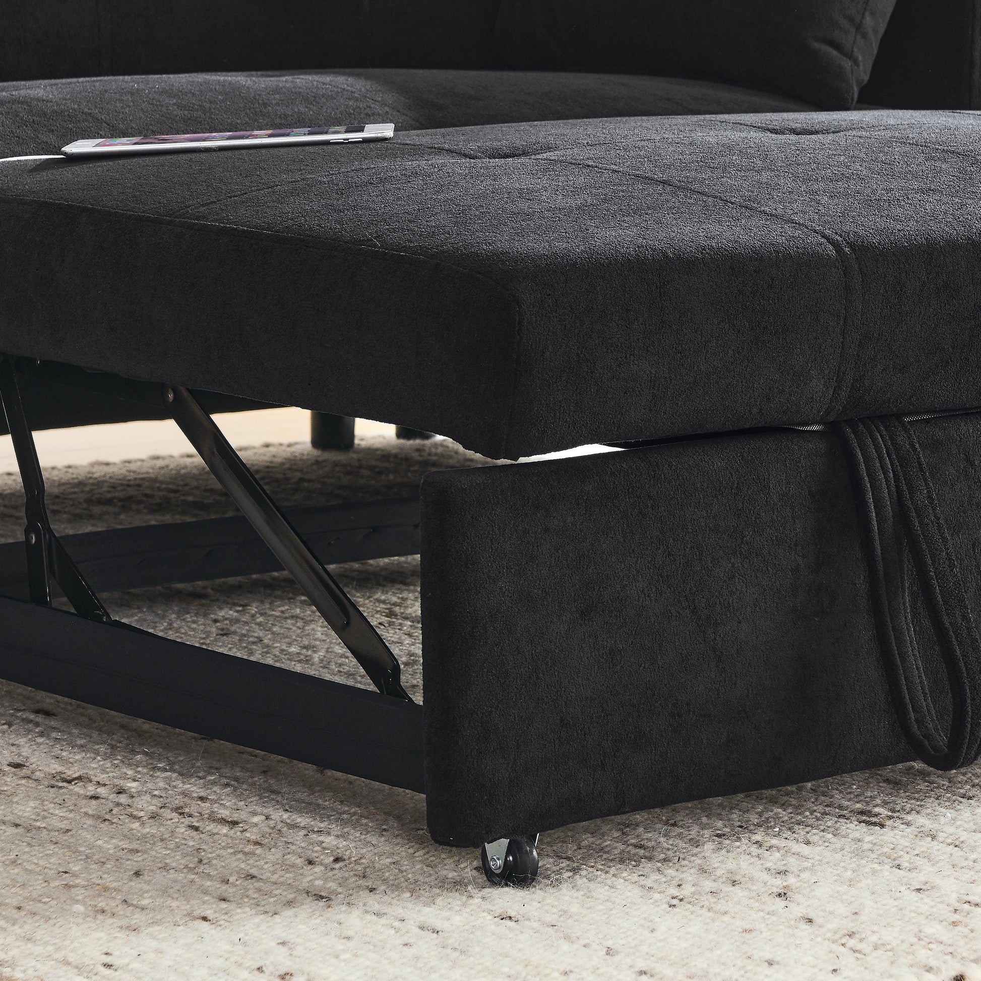 Black fabric sectional sofa with pullout storage compartment and hidden mechanism visible