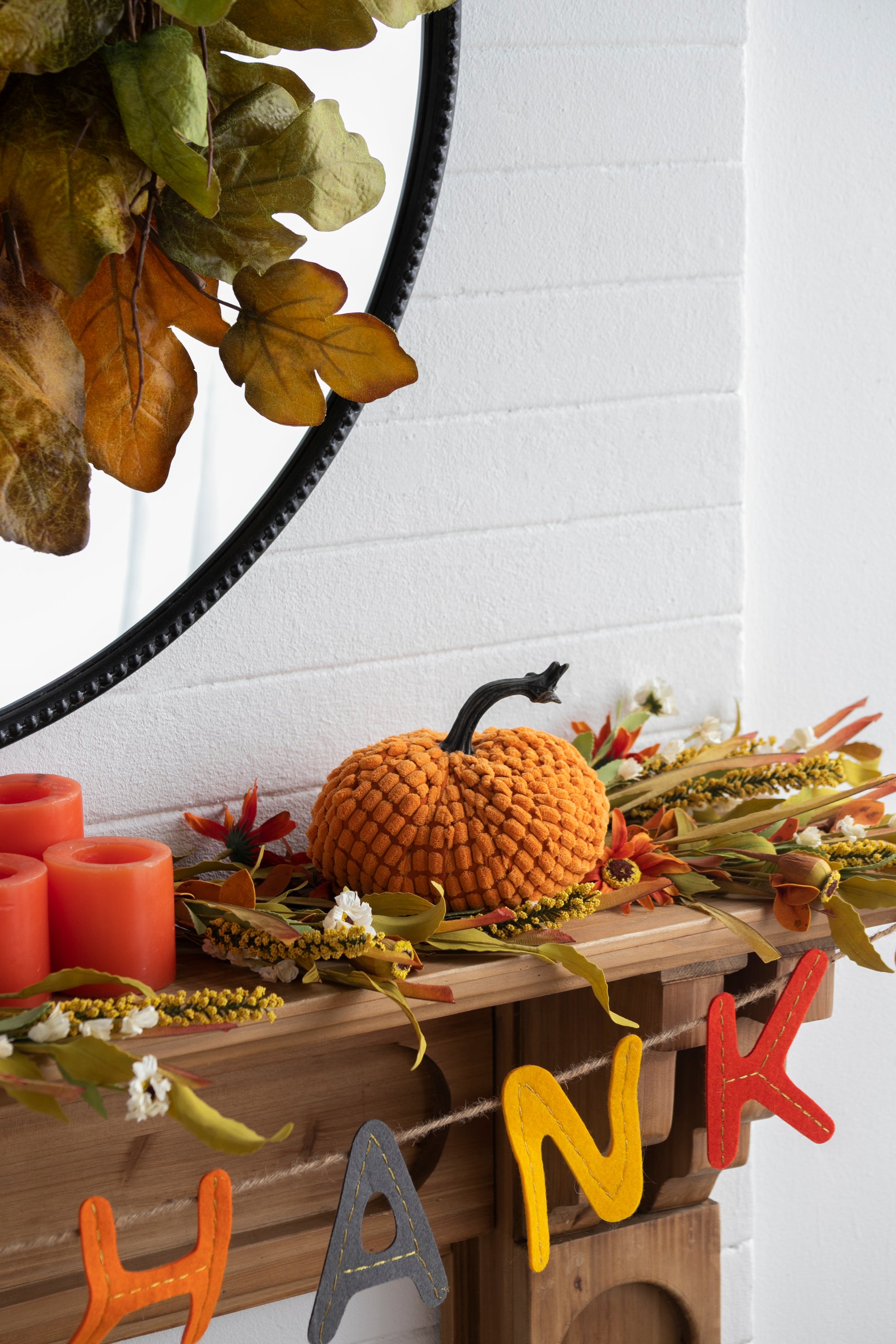 Orange textured pumpkin decor with a black stem and autumn leaves