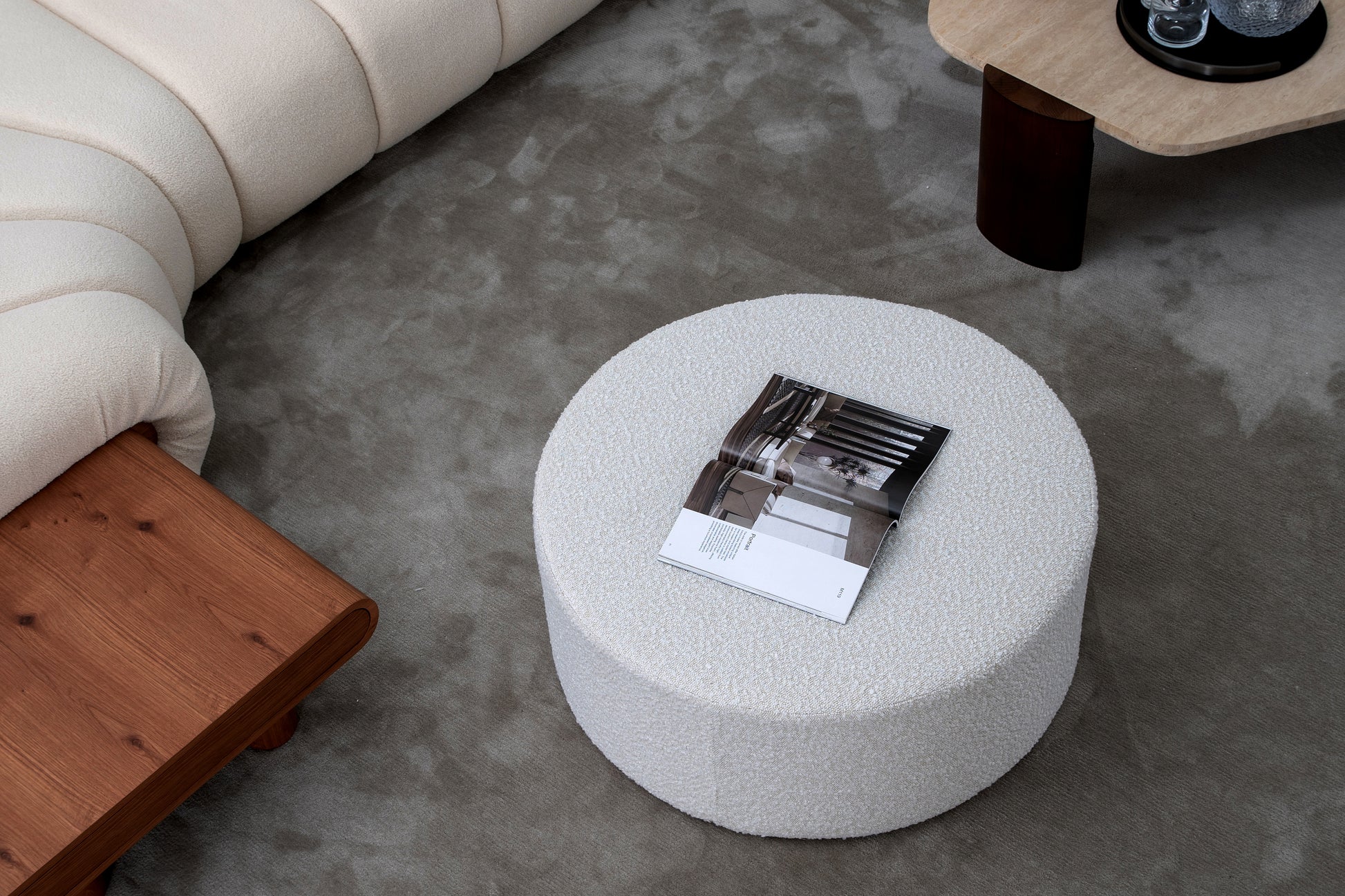 Plush ivory boucl ottoman with an open interior design magazine and a modern coffee table