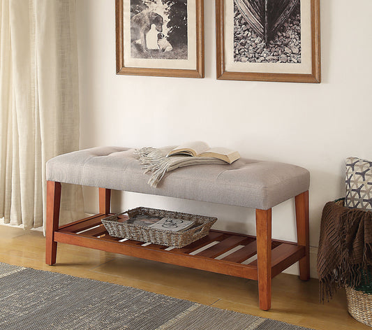 Tufted grey upholstered bench with wooden legs and slatted shelf