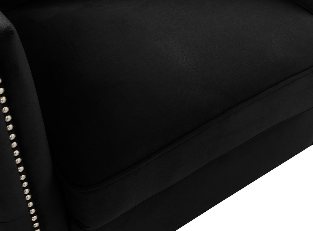 Closeup of a plush black velvet armchair with silver nailhead trim detail