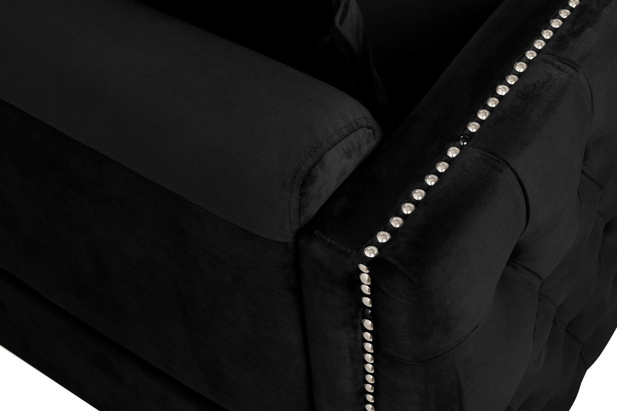 Closeup of a black velvet armchair with silver stud trim on the armrest
