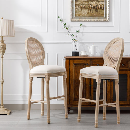 Two light wood cane back bar stools with cream upholstered seats