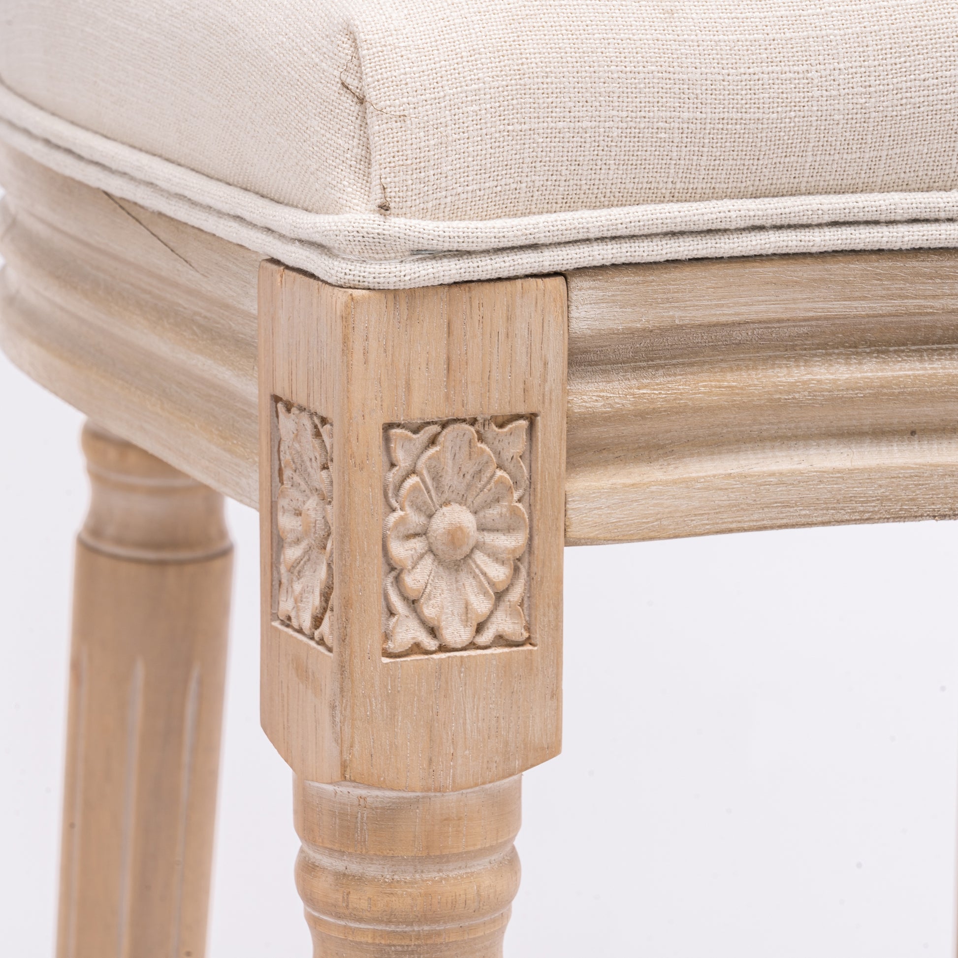 Closeup of carved floral detail on a light wood stool leg