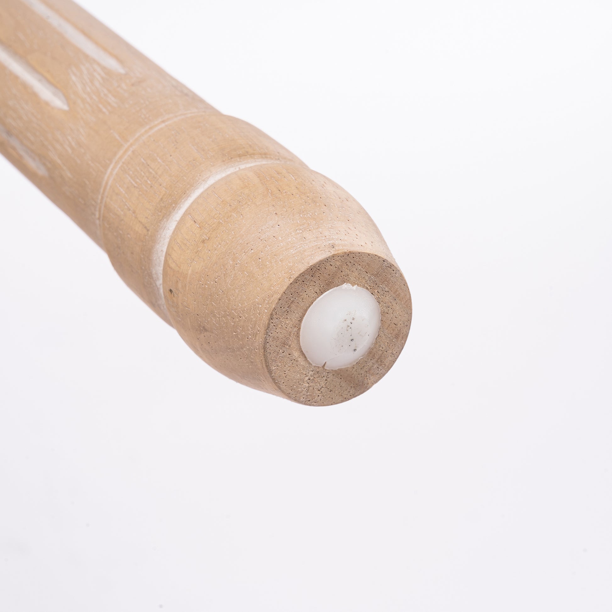 Closeup of a light brown wooden rolling pin handle with textured finish and subtle white accents