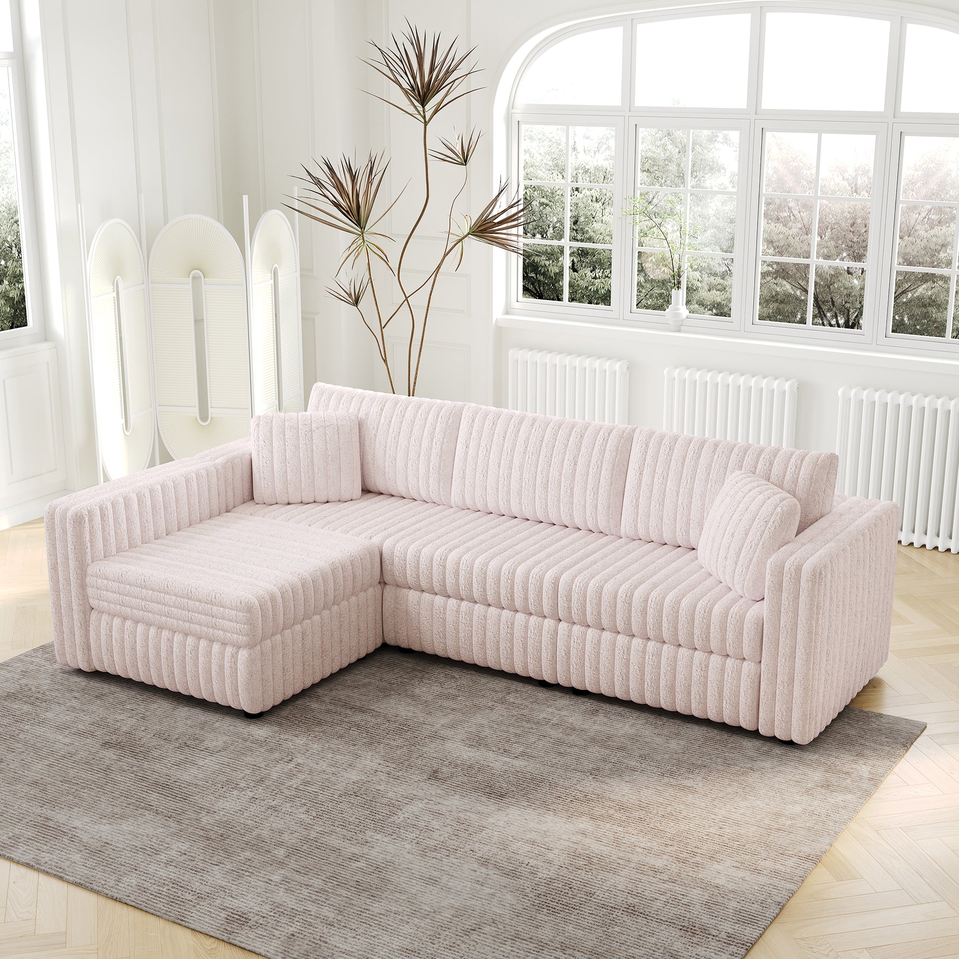 Pink corduroy sectional sofa with plush pillows on a patterned rug in a bright living room