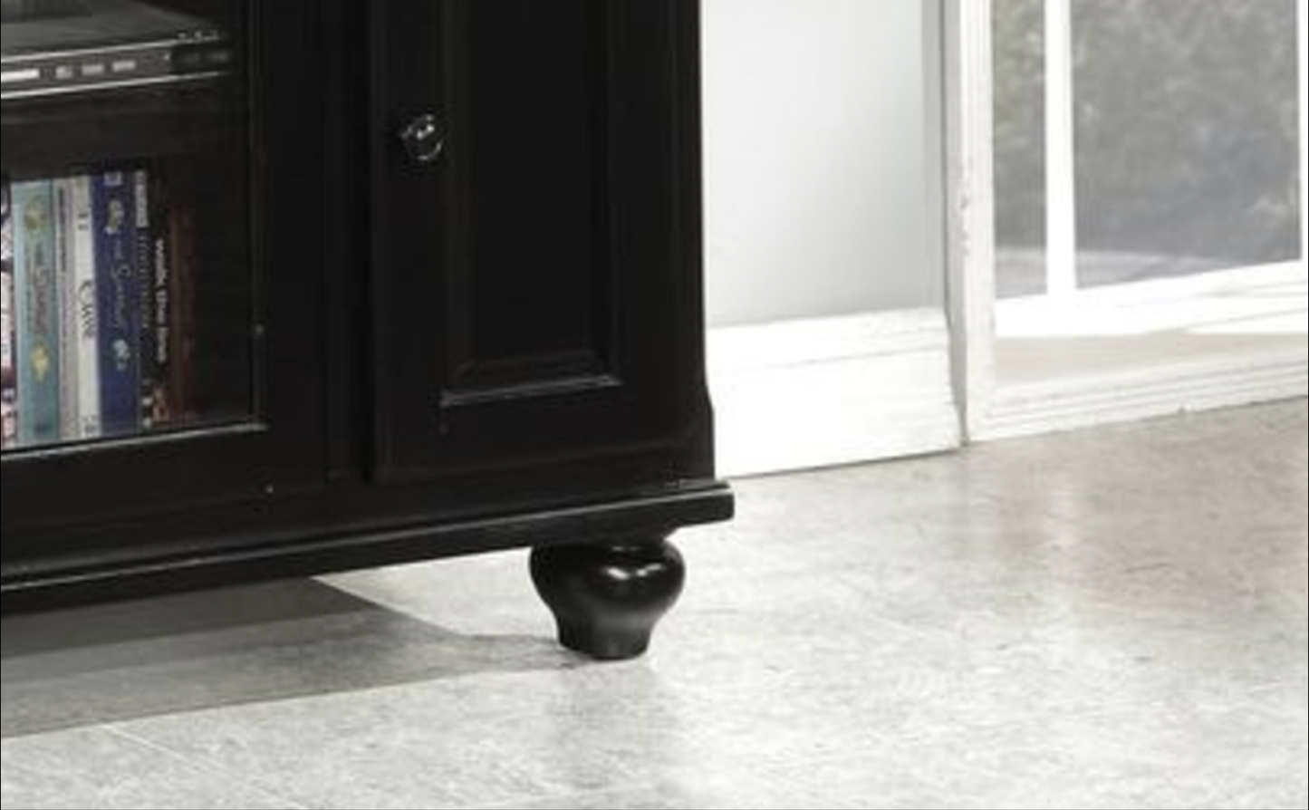 Black wooden media console with glass door showcasing DVDs