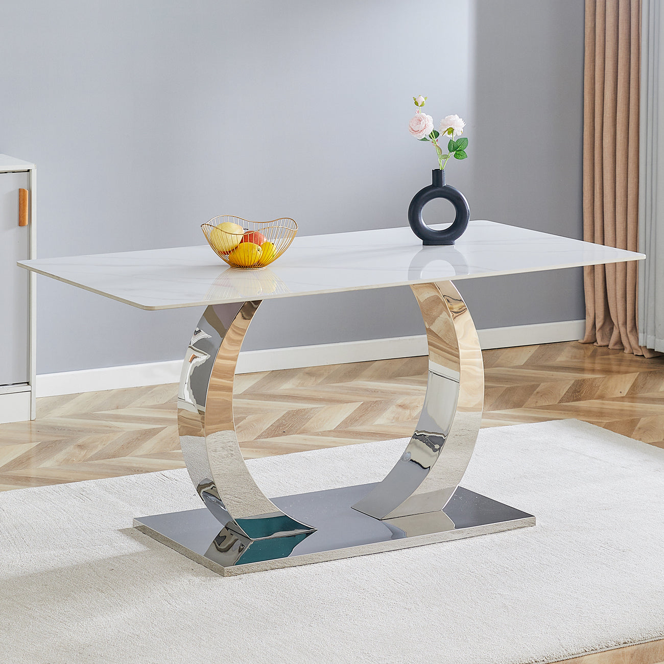 Modern white marble dining table with a polished chrome pedestal base and fruit bowl