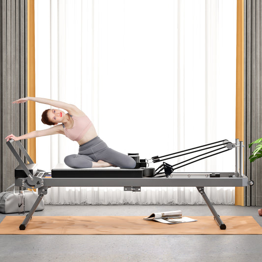 Woman stretching on a gray Pilates reformer with resistance bands
