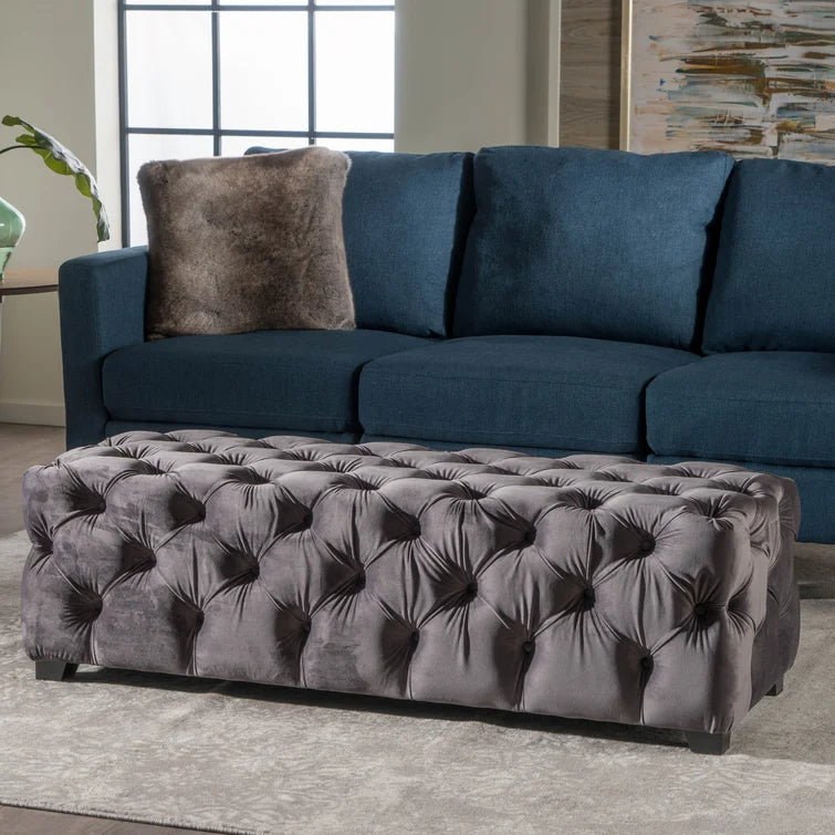 Tufted grey velvet rectangular ottoman with button detailing and black legs