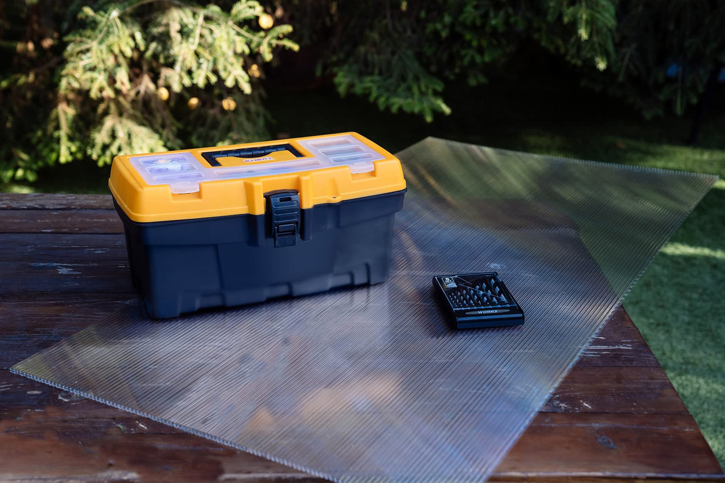 Yellow and black plastic toolbox with clear organizer lid on wooden table