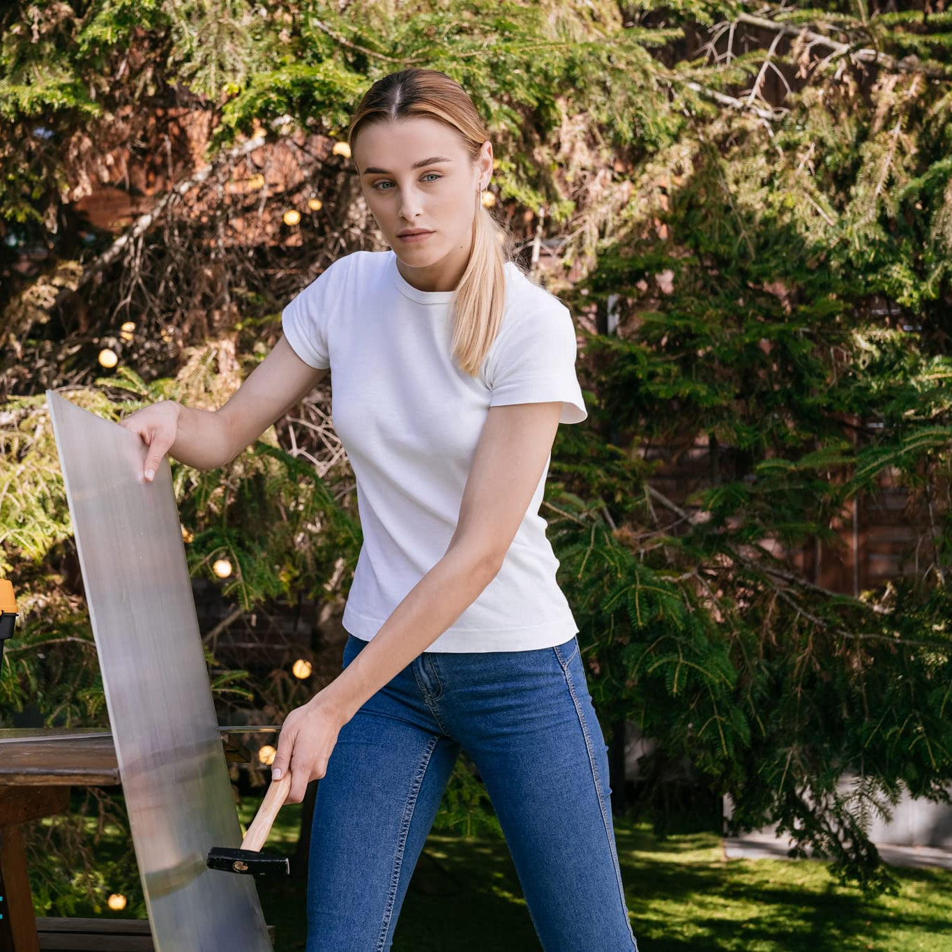 Young woman in white tshirt and blue jeans holding a large clear acrylic sheet