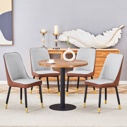 Four light gray upholstered dining chairs with brown trim and black goldtipped legs around a wood table