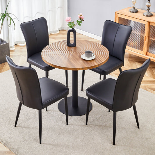Four black faux leather dining chairs with sleek modern design around a round wooden table