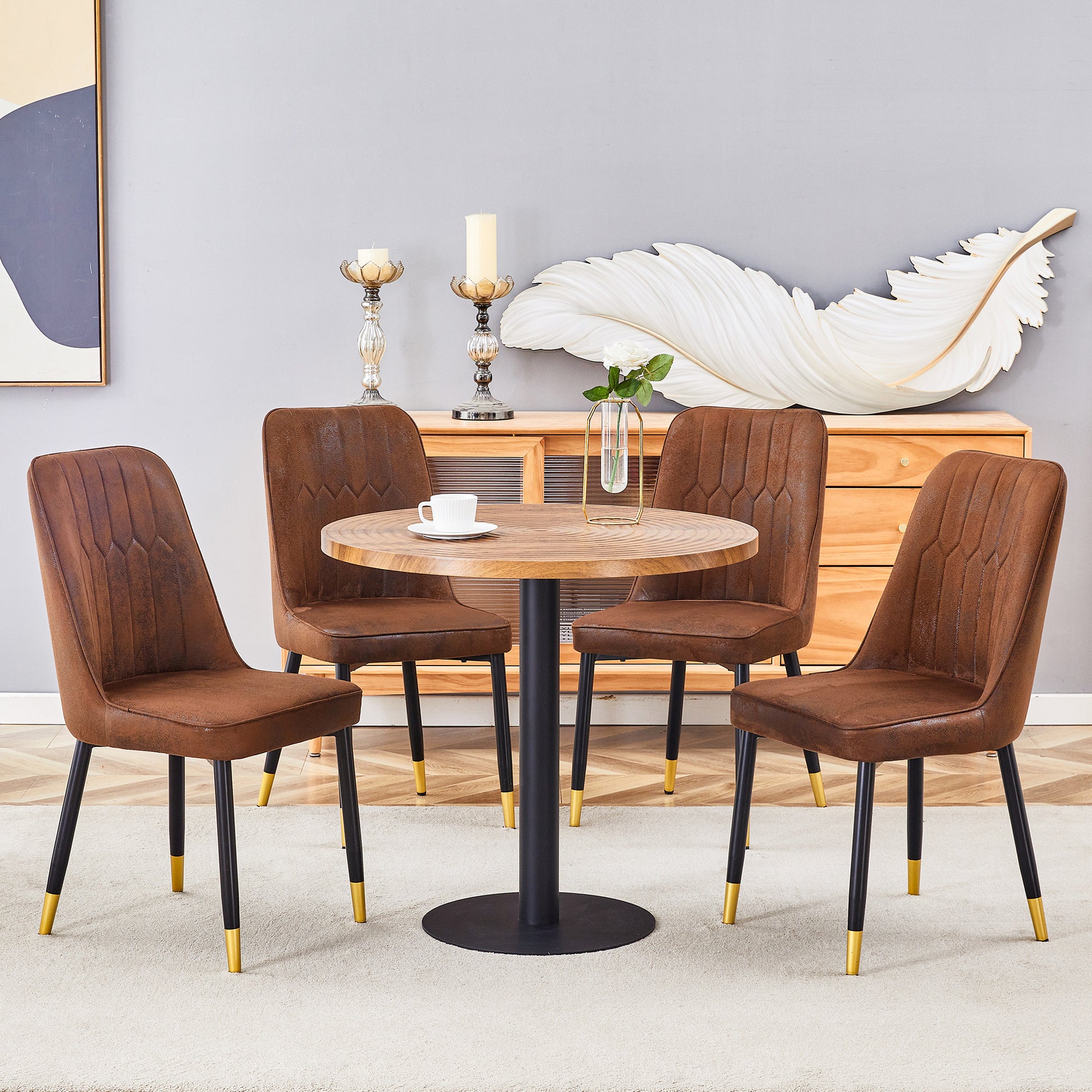 Four brown faux leather dining chairs with goldtipped black legs arranged around a round wood table