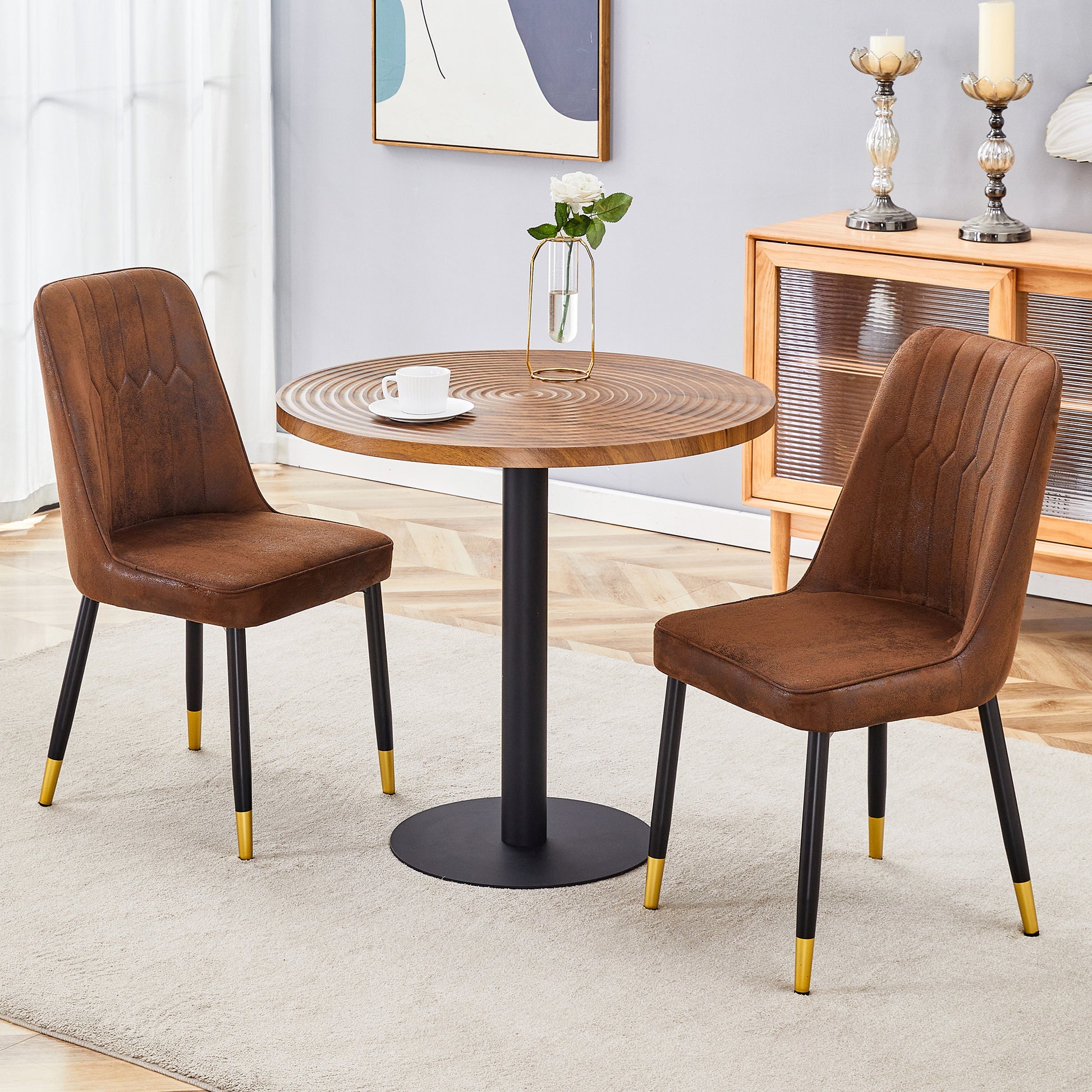 Two brown faux leather dining chairs with goldcapped black legs