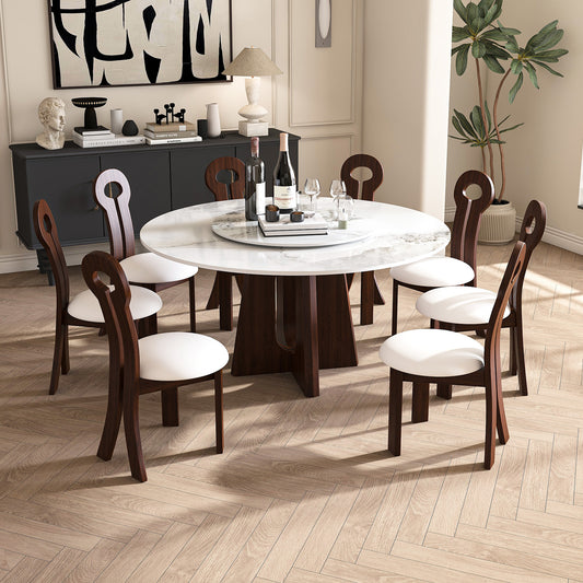 Round marble dining table with white upholstered chairs and dark wood accents