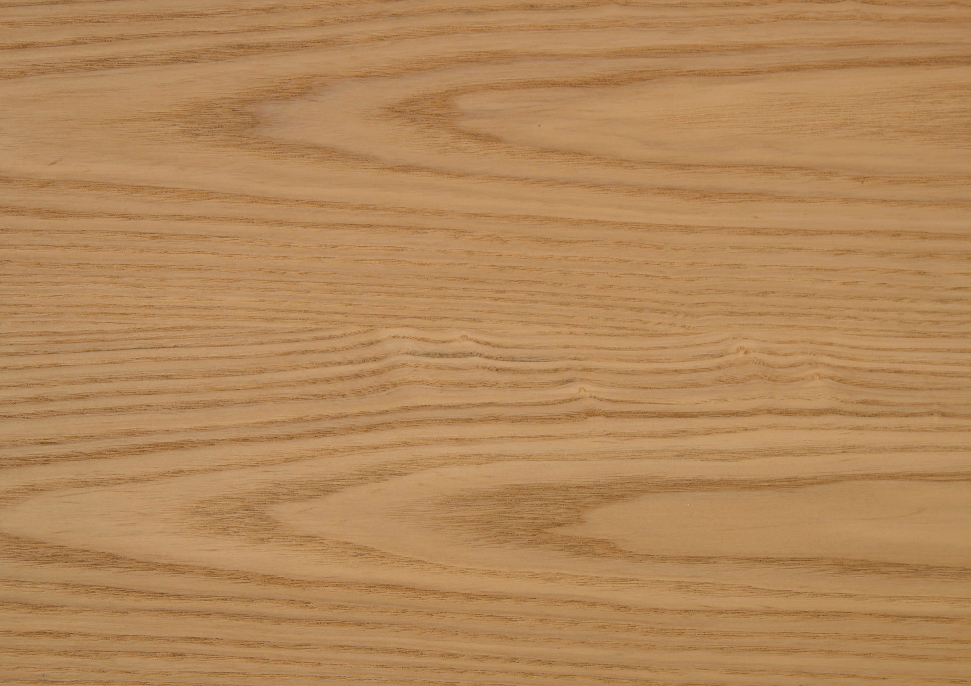 Closeup of natural ash wood grain showcasing wavy patterns and warm light brown tones
