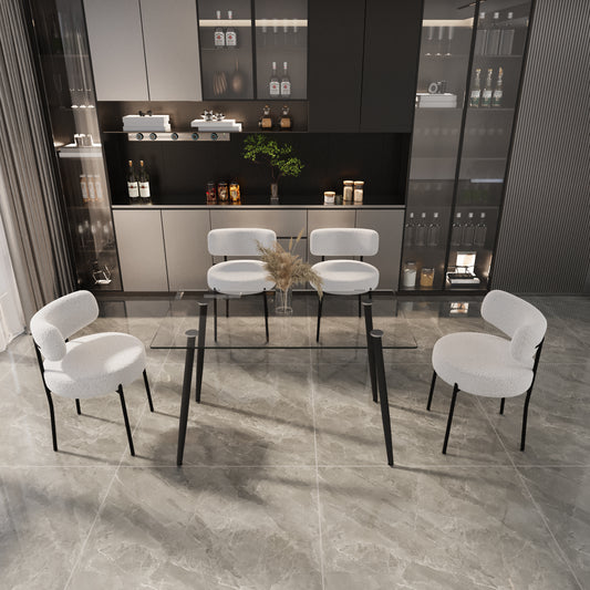 Four white boucle dining chairs surround a clear glasstop table with black metal legs