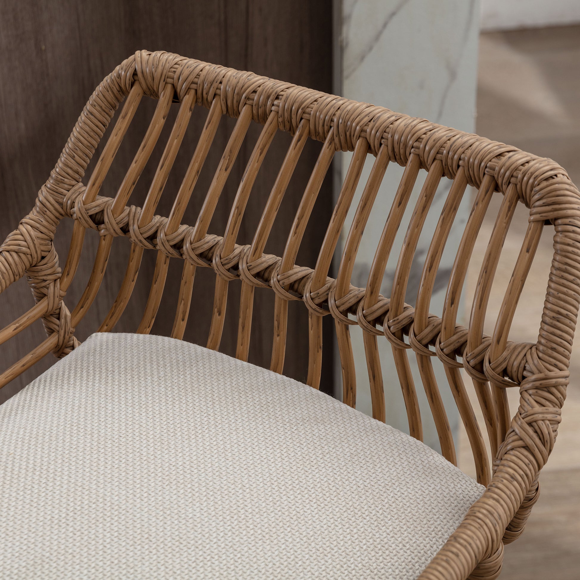 Natural rattan accent chair with a woven back and light cream cushion