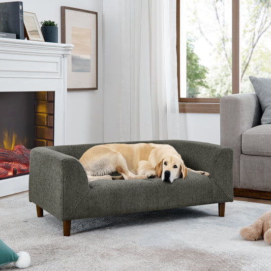 A golden retriever dog rests on a dark grey upholstered dog sofa with wooden legs
