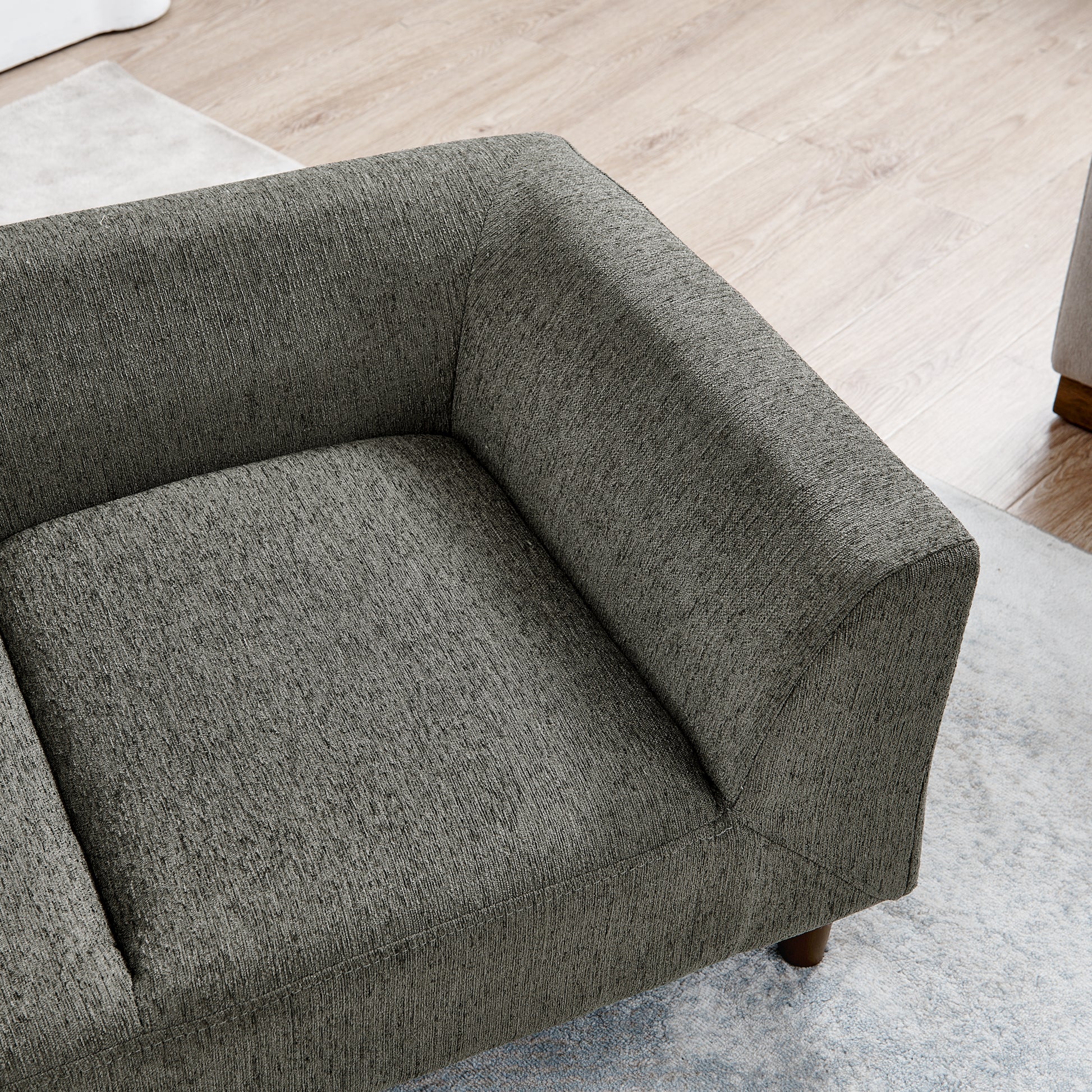 Closeup of a charcoal grey textured fabric sofa arm and seat cushion