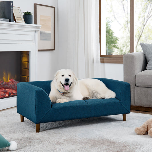 Deep teal upholstered dog sofa with wooden legs and a white fluffy dog resting on it