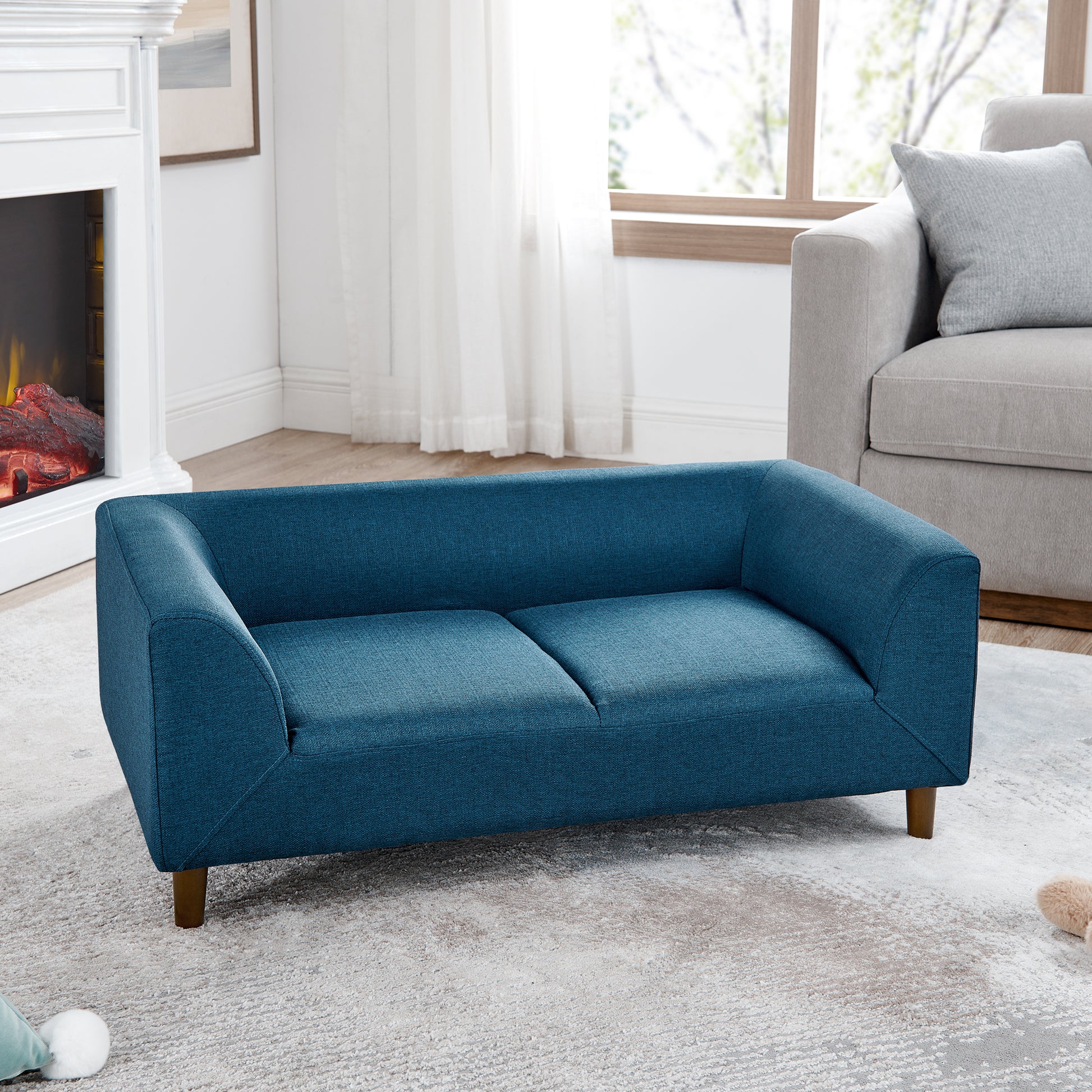 Teal fabric twoseater sofa with tapered wooden legs in a modern living room setting
