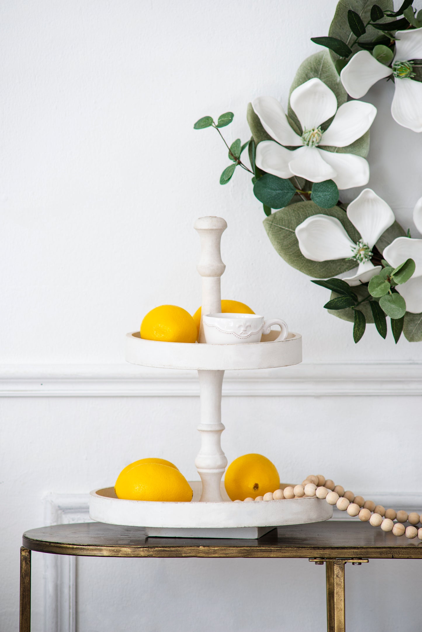White wooden tiered tray with yellow lemons and a delicate teacup