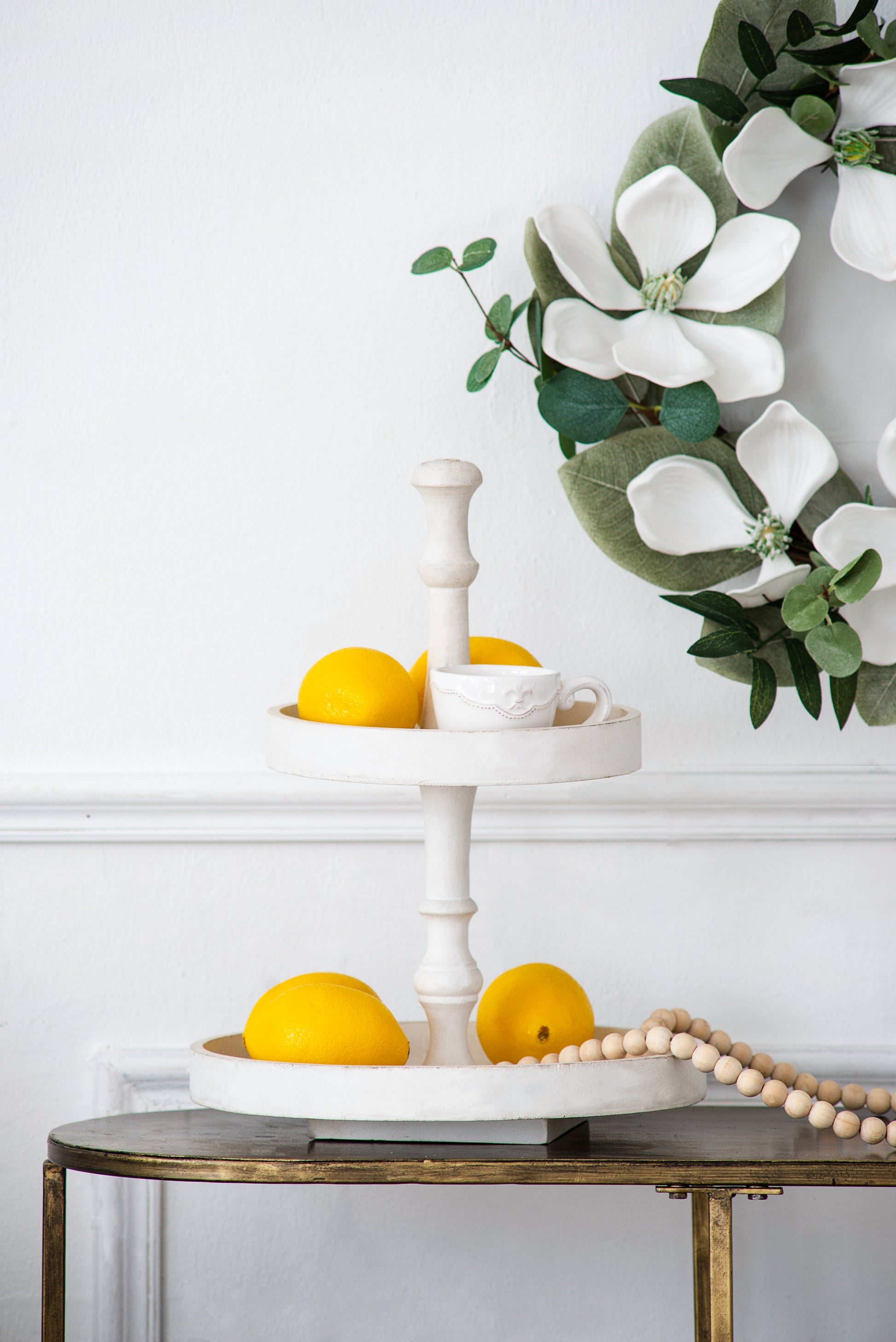 White wooden tiered tray with yellow lemons and a delicate teacup