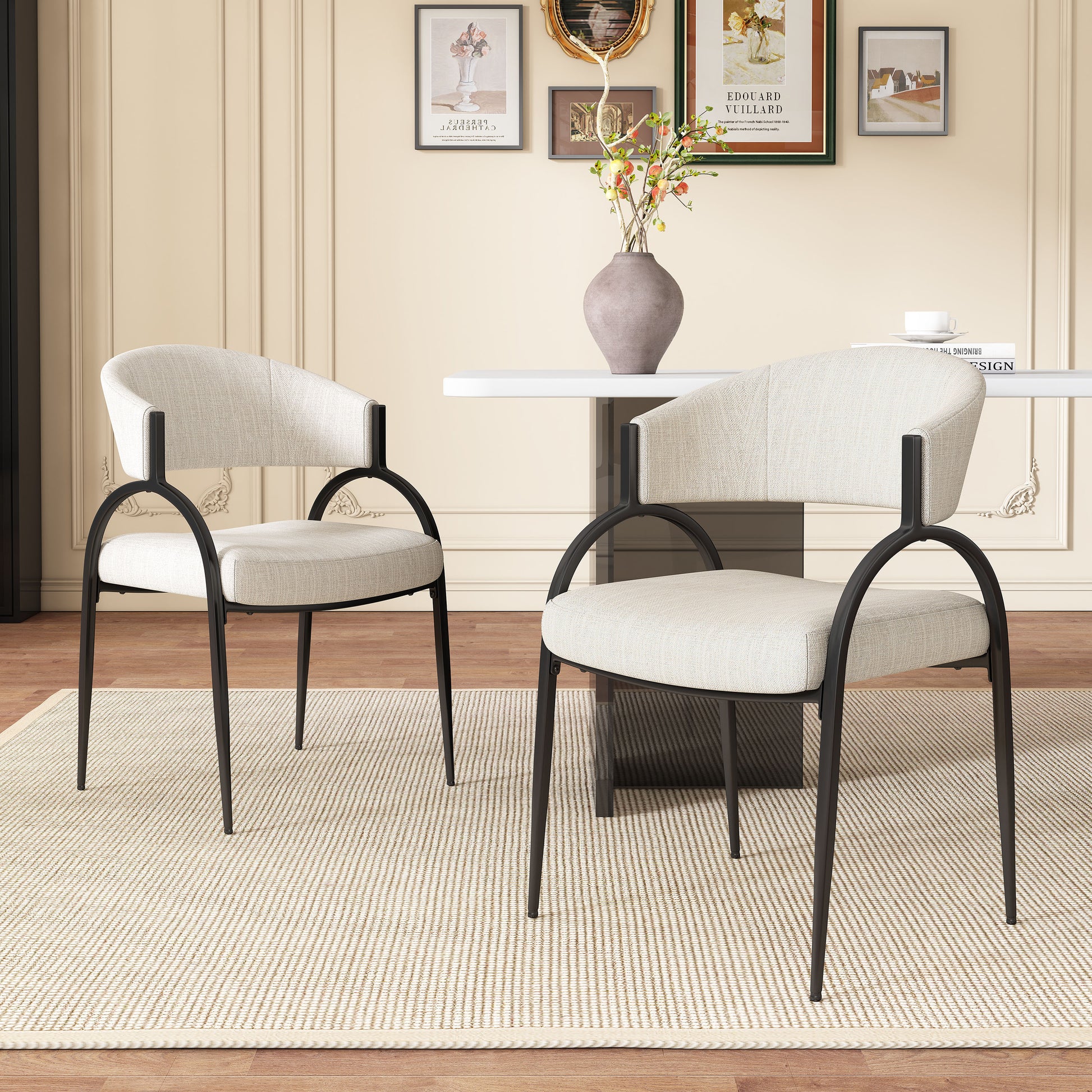 Two modern upholstered dining chairs with black metal frames and light beige fabric seats