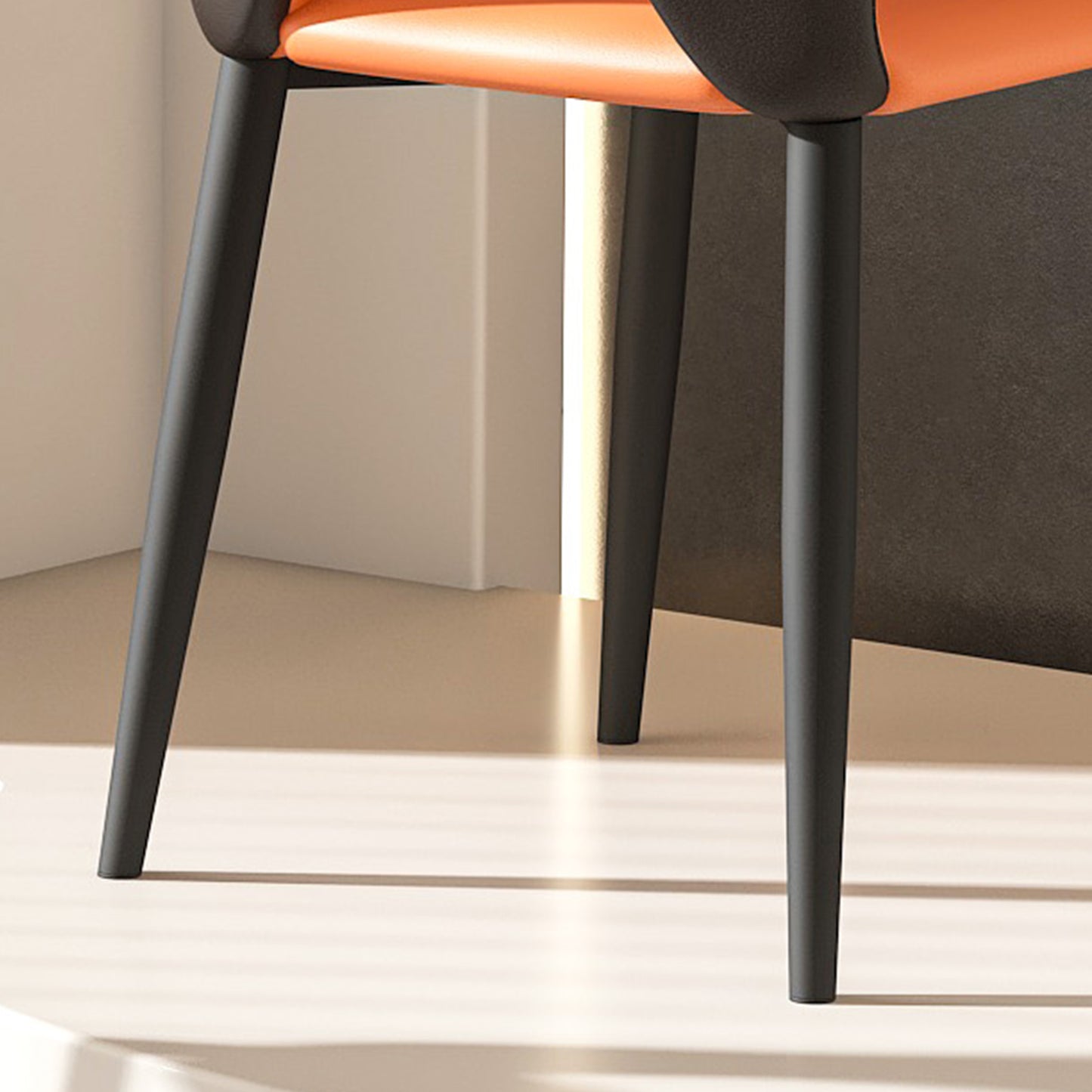 Closeup of an orange leather and charcoal upholstered chairs tapered metal legs