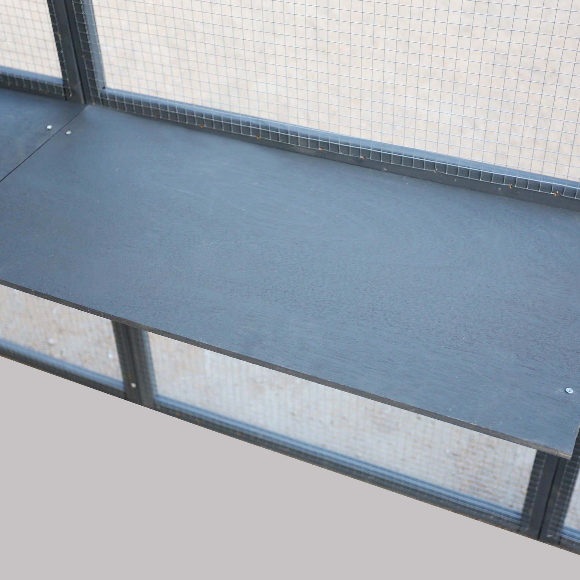 Dark gray wooden shelf inside a metal wire cage for small pets