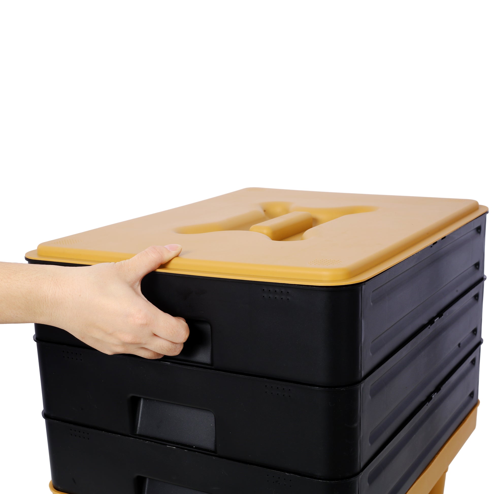 Collapsible storage bin with black body and tan lid featuring a hand holding the side handle