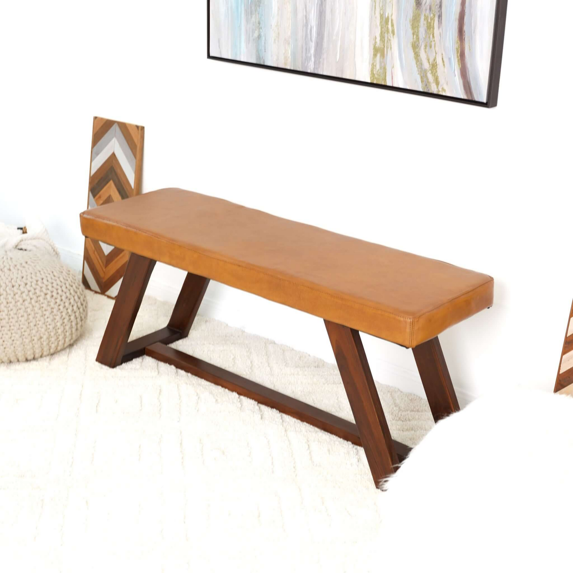 Tan leather upholstered bench with dark wood geometric base