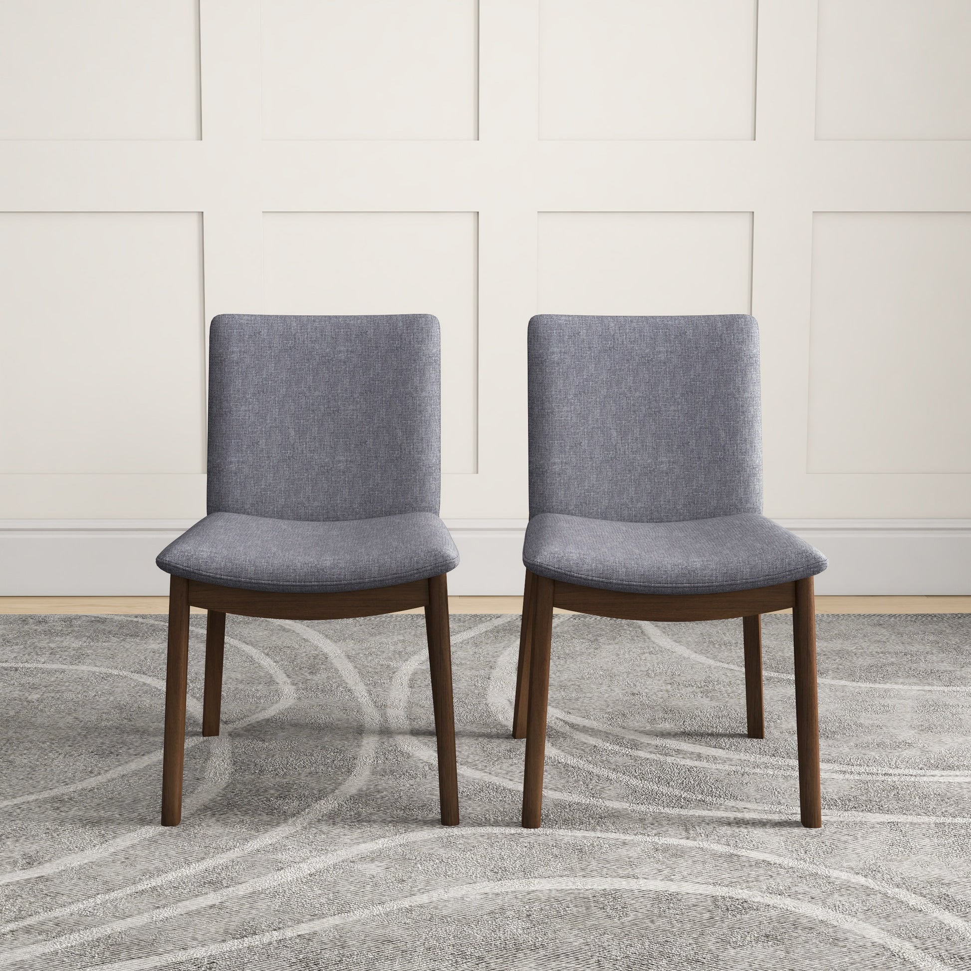 Pair of grey upholstered dining chairs with wooden legs on a patterned rug