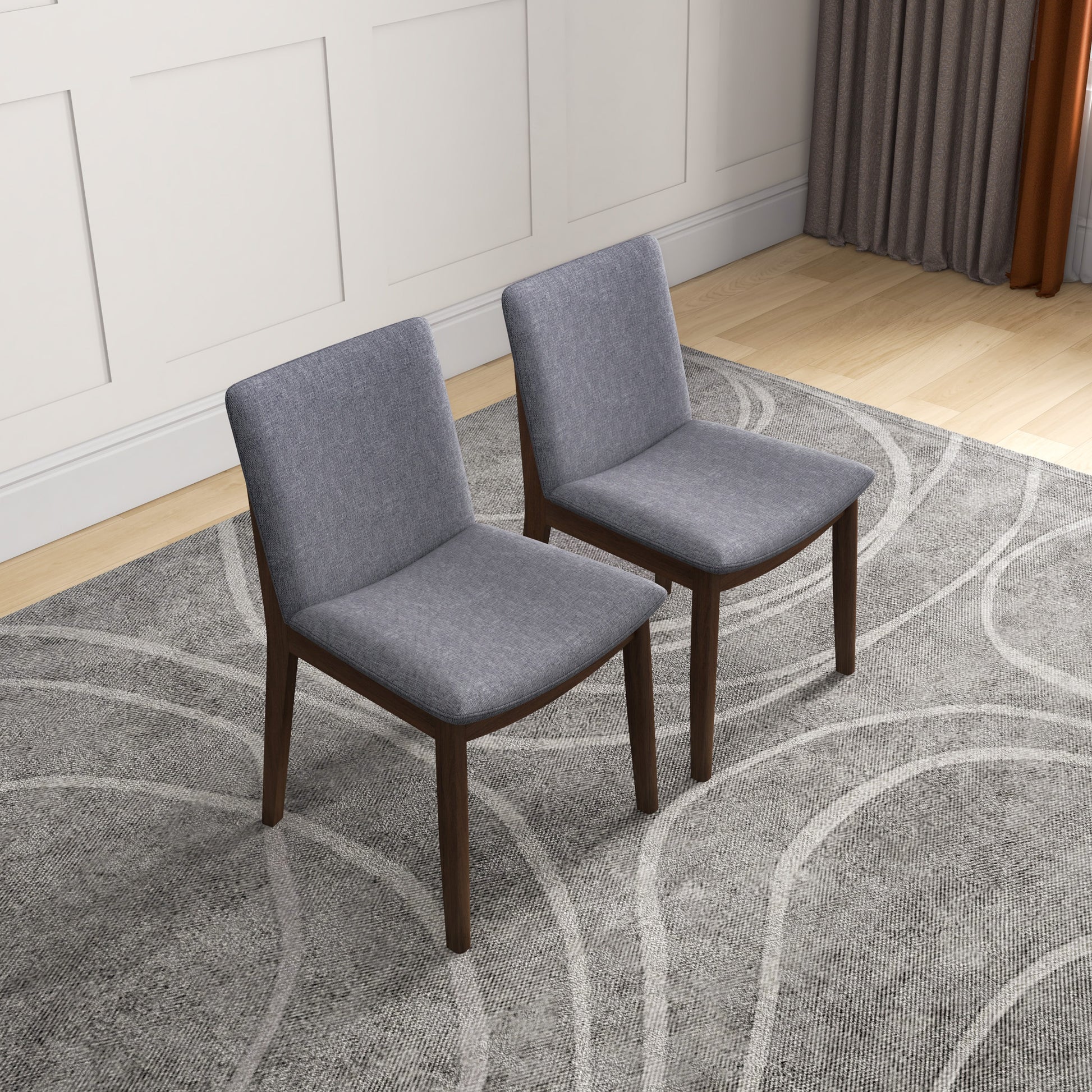Two grey upholstered dining chairs with dark wood legs on a rug