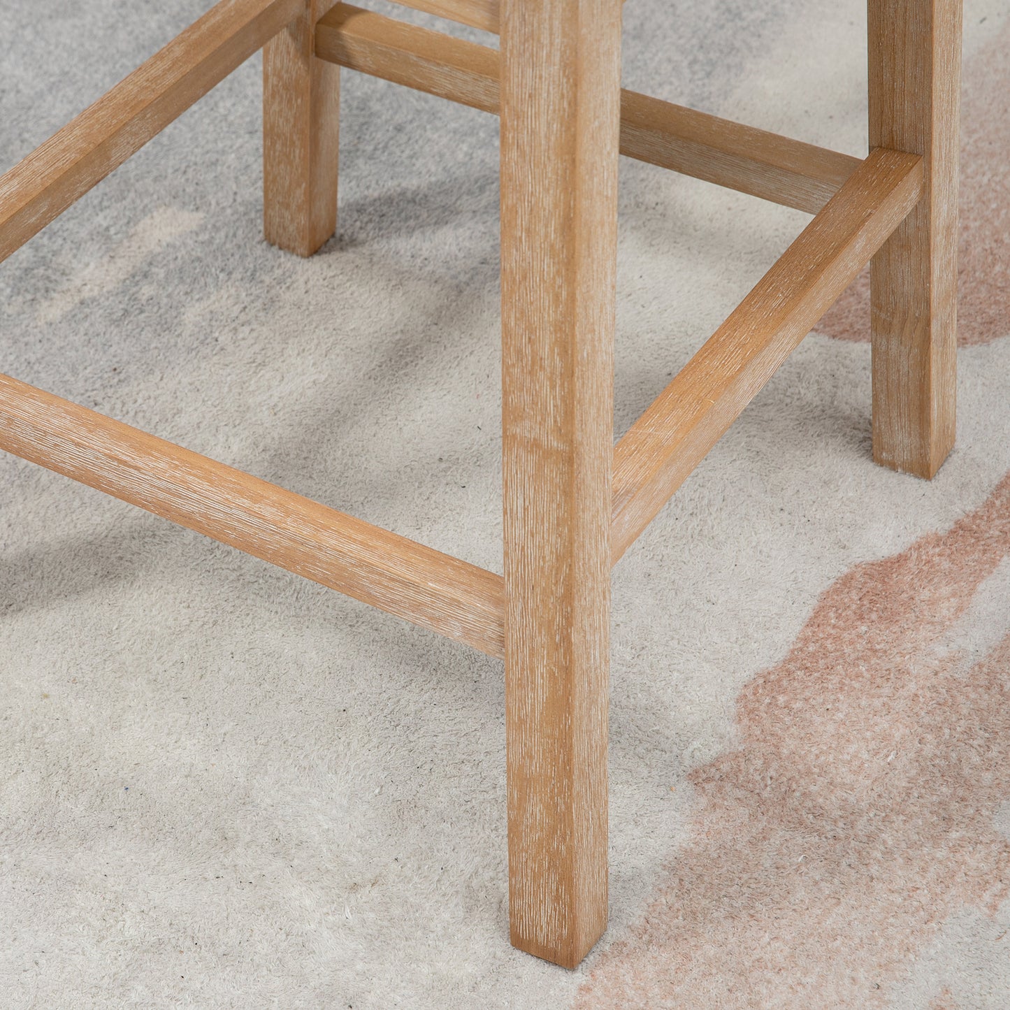 Natural oak wood stool legs with weathered finish on textured rug