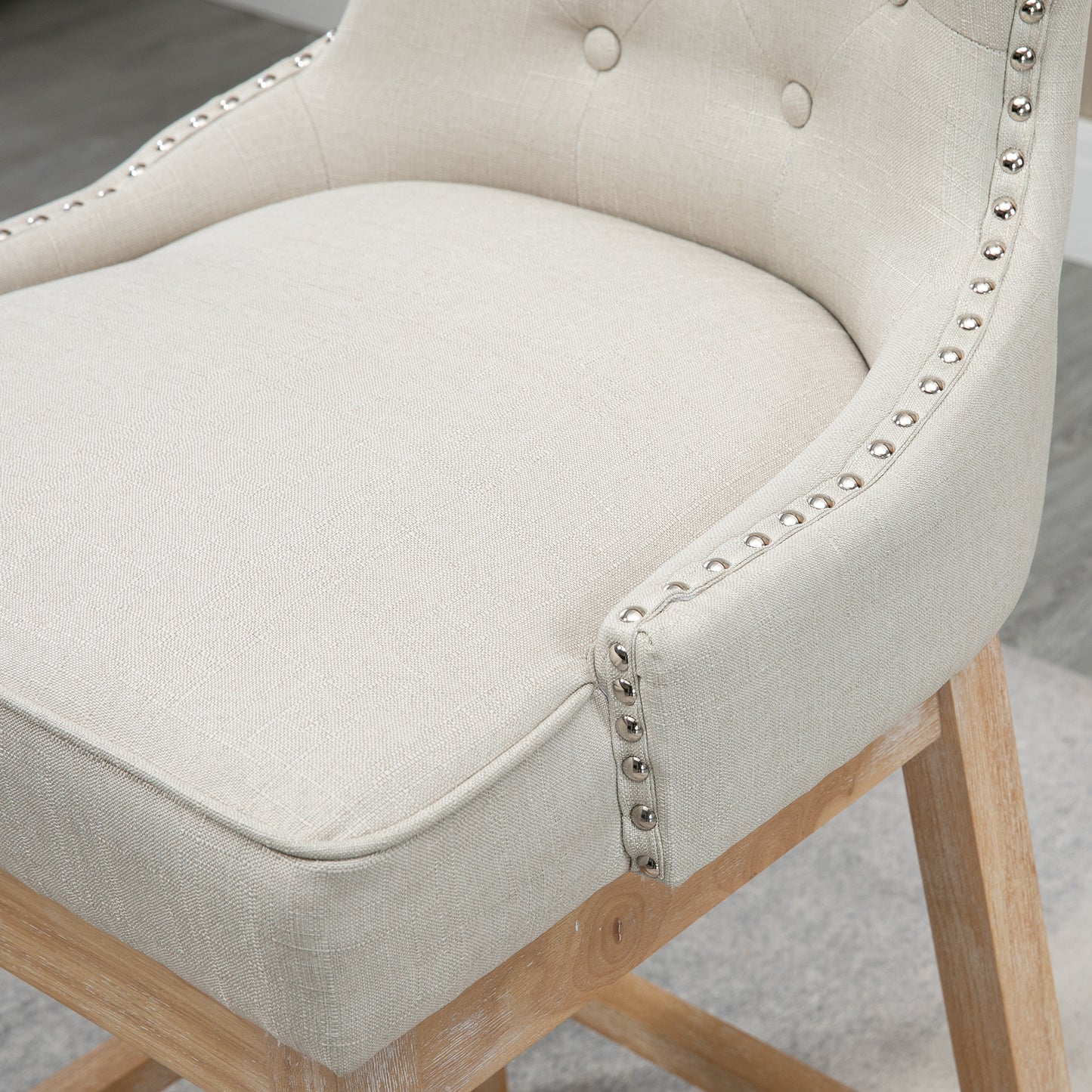 Upholstered bar stool in cream linen fabric with silver nailhead trim and wooden legs