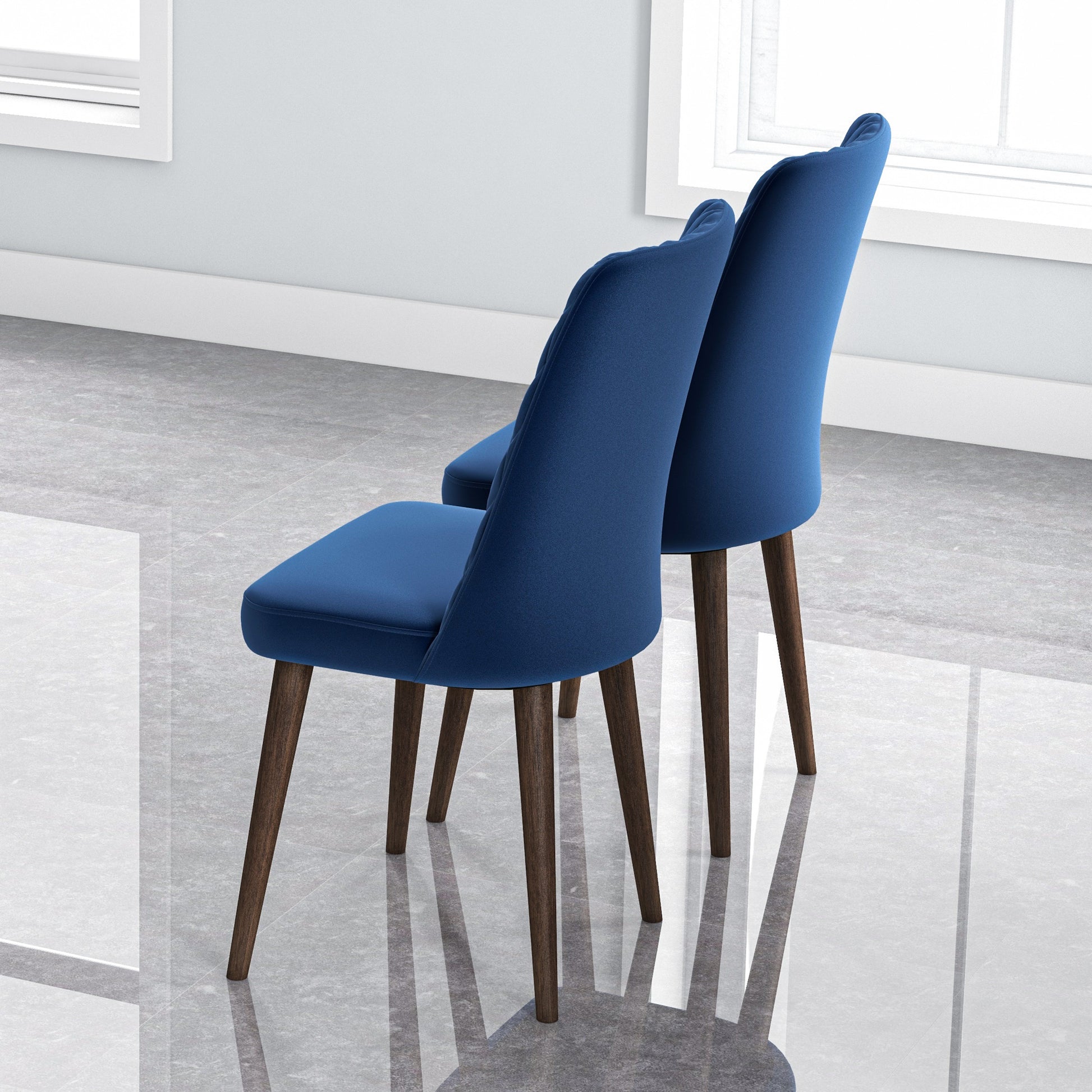 Two plush blue velvet dining chairs with dark wood legs on a glossy floor