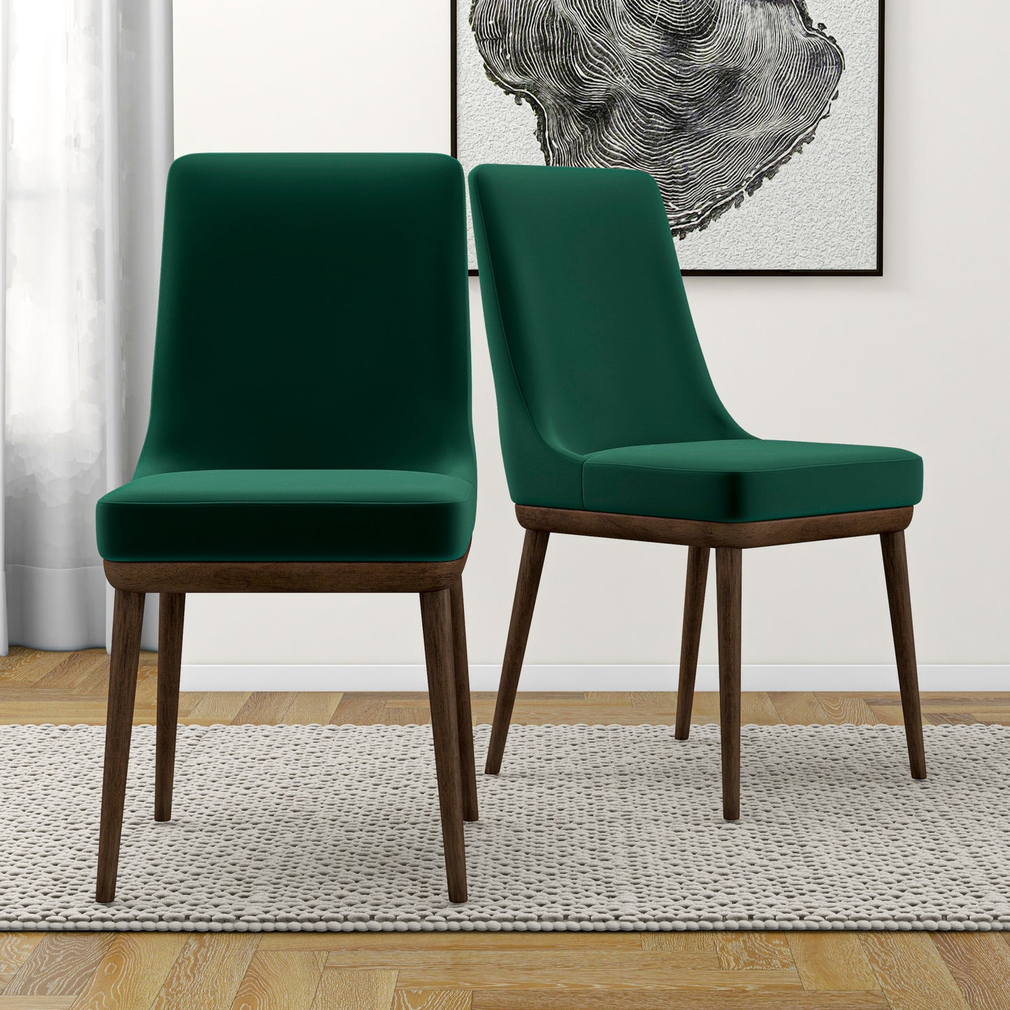 Two plush emerald green velvet dining chairs with dark wood legs on a rug
