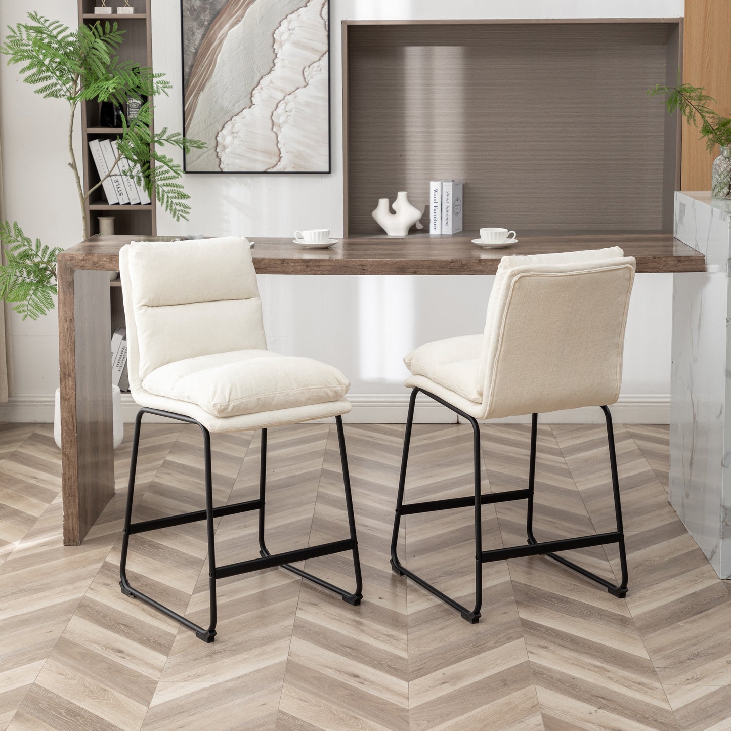 Two upholstered cream counter height bar stools with black metal legs arranged around a wooden counter