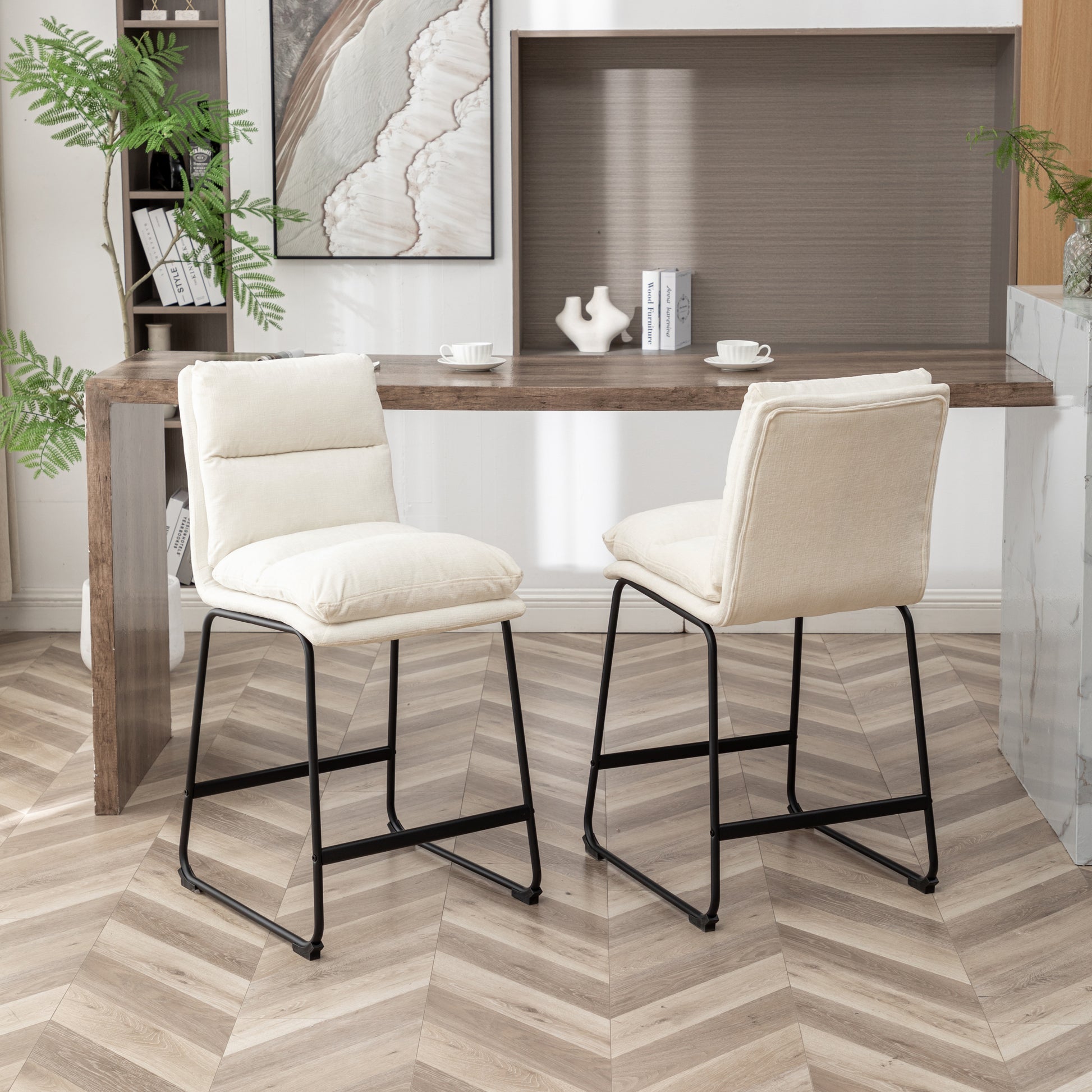 Two upholstered cream counter height bar stools with black metal legs arranged around a wooden counter