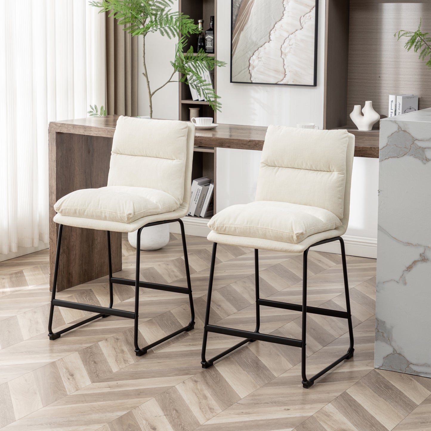 Two beige linen upholstered bar stools with tufted backs and black metal legs