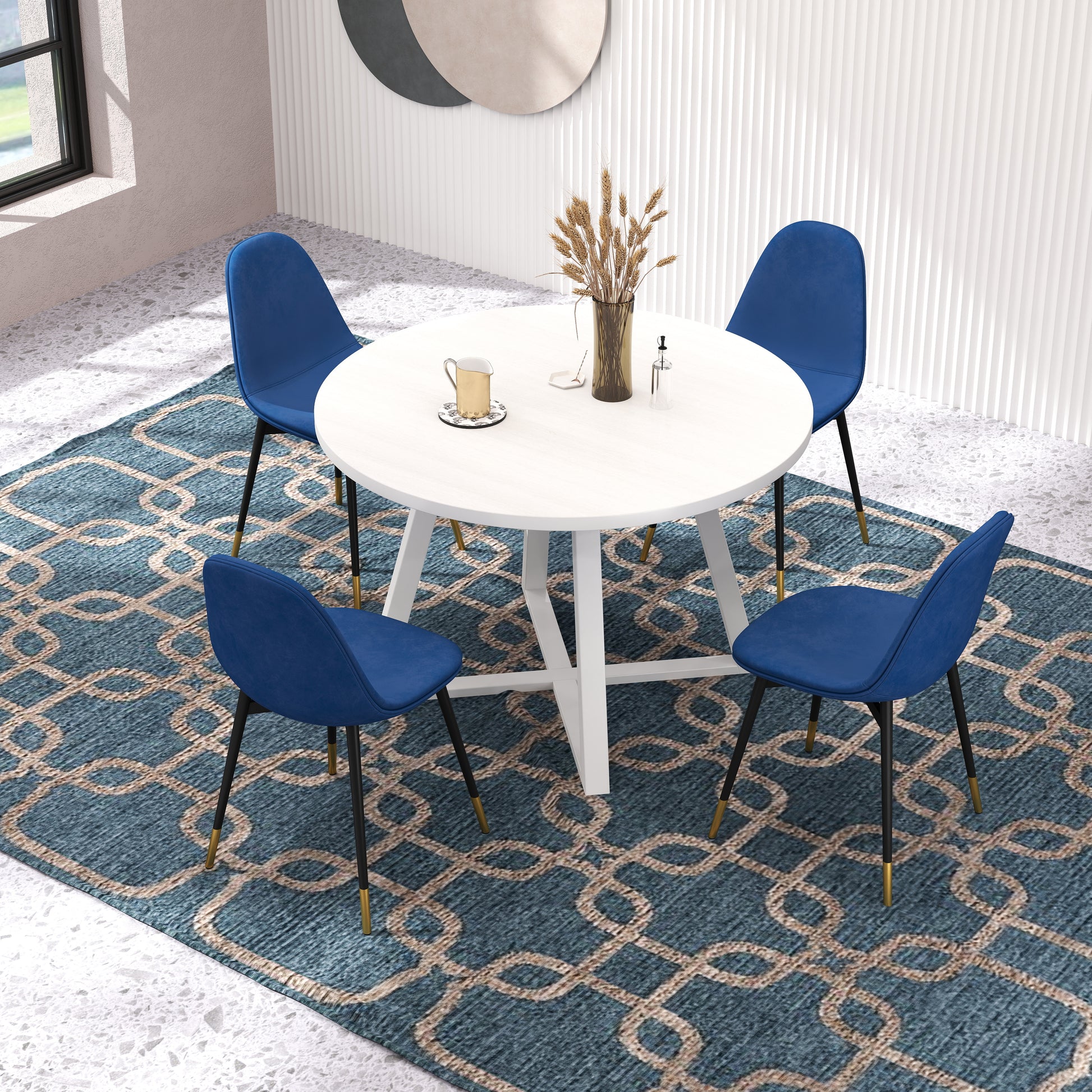 Round white dining table with four blue velvet chairs and gold accents