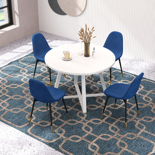 Round white dining table with four blue velvet chairs and gold accents