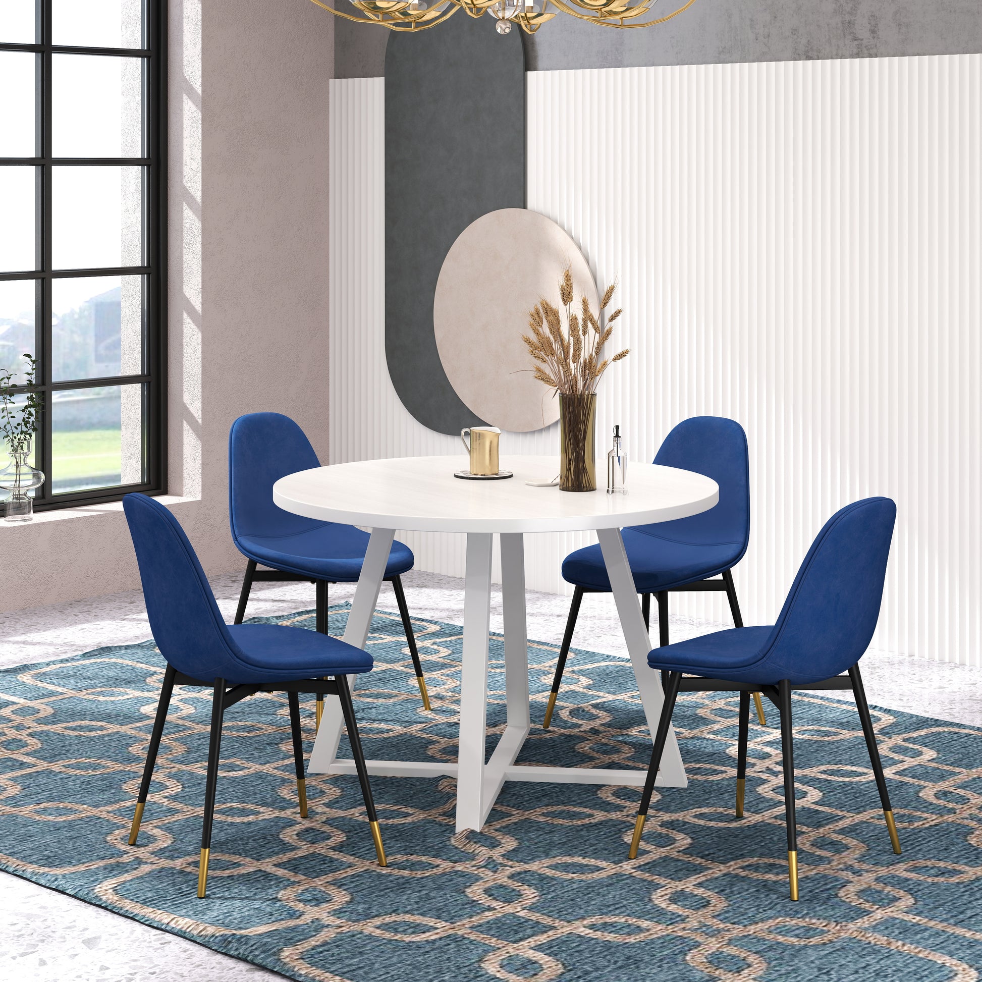 Four navy blue velvet dining chairs with goldtipped black legs arranged around a white round table