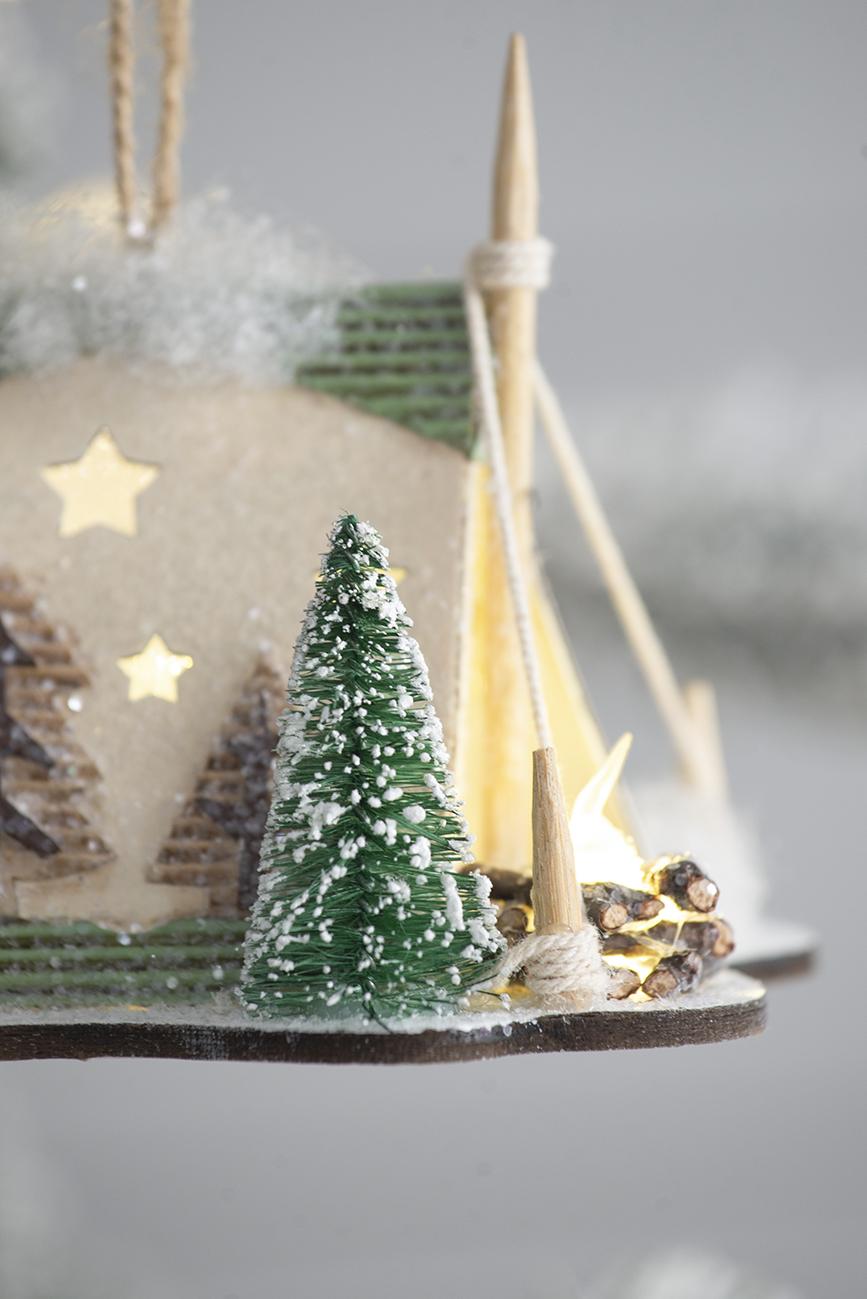Miniature flocked pine tree with snow accents part of a rustic winter village scene
